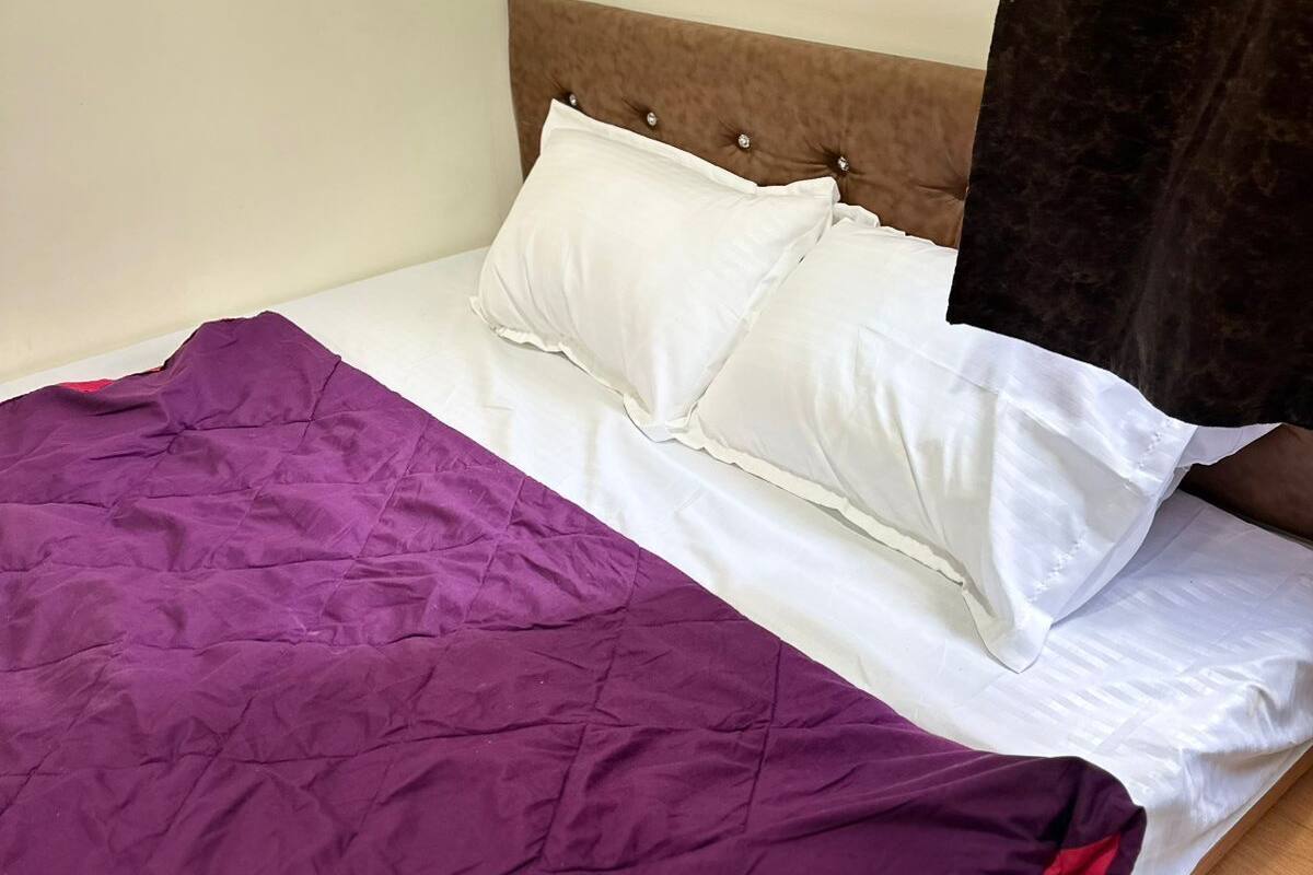 A bed with a purple blanket, white pillows, and a wooden headboard.