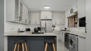 A modern kitchen with a central island, built-in appliances, and bar stools.