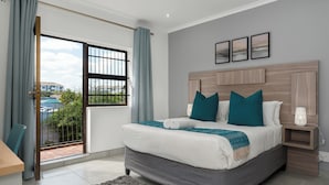A bedroom with a large bed, a nightstand, a window with curtains, and a view of the outside.