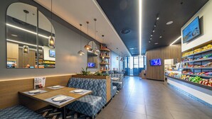 Un restaurant moderne doté d’une salle à manger, d’un bar servant des collations et d’un écran de télévision.