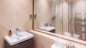 A modern bathroom with a vanity, sink, mirror, toilet, and shower. - The Courtfield - Studio Lower Ground in Kensington (London)