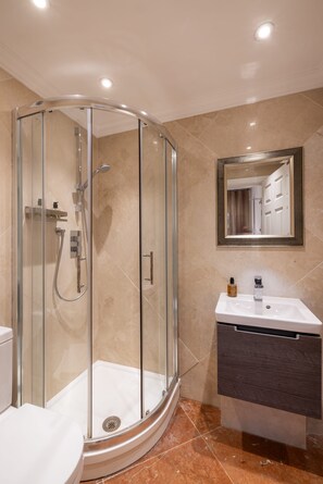 A modern bathroom with a glass-enclosed shower, a vanity with a mirror, and a toilet.