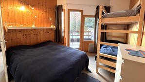 Ein Zimmer mit einem Etagenbett, einem Schreibtisch und einem Fenster mit Blick auf eine Holzterrasse.