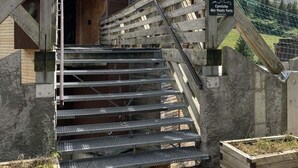 Eine Holztreppe führt zu einem Gebäude, an dem ein Schild mit der Aufschrift 'Corniche des Hauts Forts' befestigt ist.