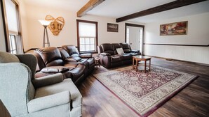 Ein Wohnzimmer mit Ledersofas, einem gemusterten Teppich und einer Stehlampe.