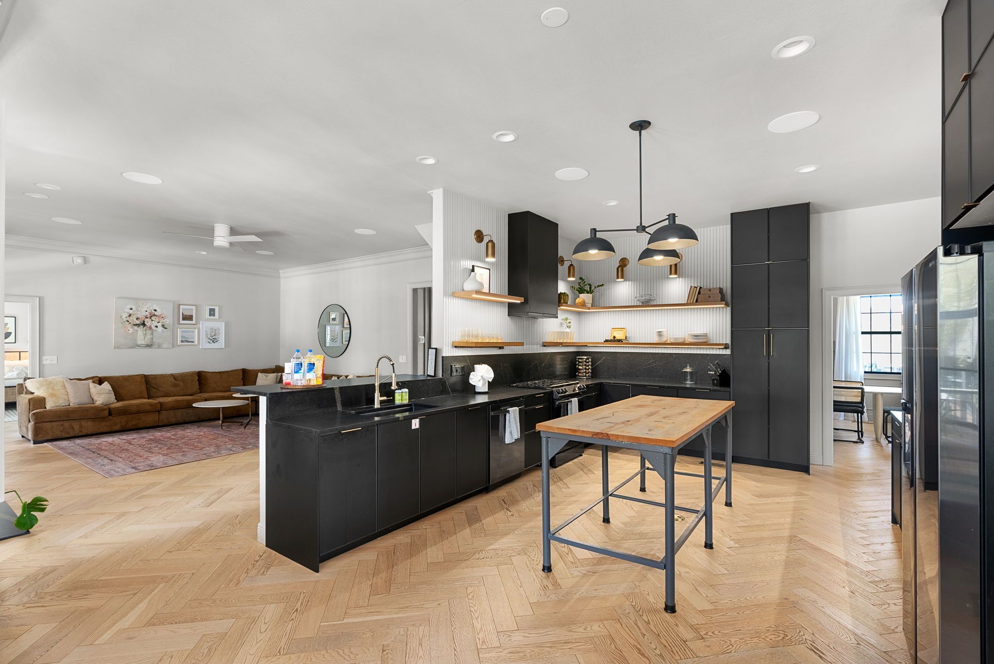 A modern kitchen with a central island, black cabinetry, and pendant lighting.