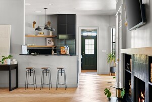 A modern kitchen with a central island, bar stools, and a fireplace.