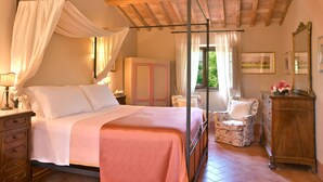 Une chambre à coucher avec un lit à baldaquin, une armoire en bois, une chaise et une commode.