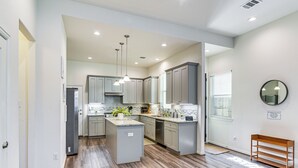 A modern kitchen with grey cabinets, a central island, and a wooden bench. - 5 Mi to Downtown - Chic Home w/ Patio in Houston! (Houston)