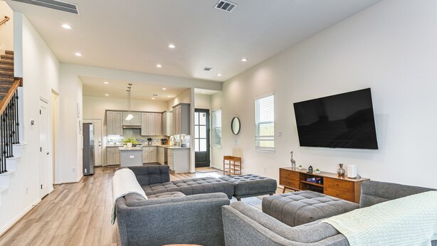 A modern living room with grey sofas, a wooden coffee table, and a TV mounted on the wall. - 5 Mi to Downtown - Chic Home w/ Patio in Houston! (Houston)