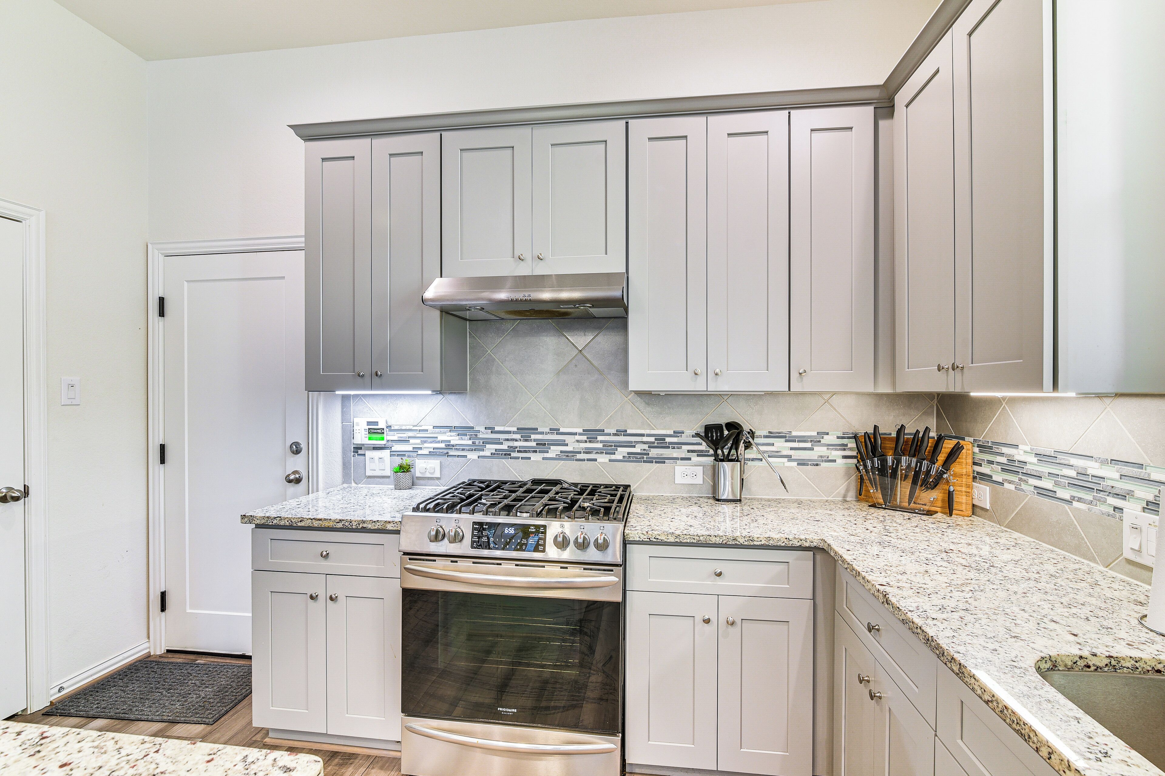 A kitchen with white cabinets, a stainless steel stove, and a tiled backsplash.