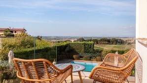 Ein Balkon mit Korbstühlen, einem kleinen Pool und Blick auf die Landschaft.