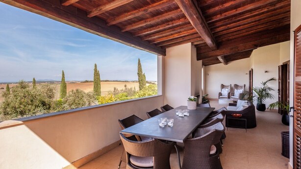 Eine überdachte Terrasse im Freien mit Tisch und Stühlen, mit Blick auf eine reizvolle Landschaft.