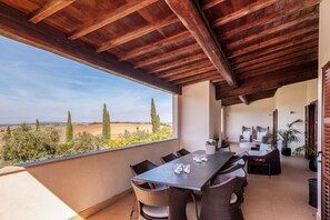 A covered outdoor patio with a table and chairs, overlooking a scenic landscape.