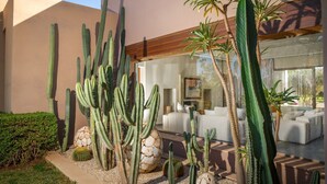 A modern building with a living room featuring a large window, a cactus garden, and a minimalist design. - Villa Azkar - Three Bedroom Villa, Sleeps 6 (Marrakesh)
