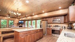 A spacious kitchen with wooden cabinets, a large island, stainless steel appliances, and a view of the outdoors. - Epic Stay: Private Pool, Theater & Games for 30 (Sevierville)