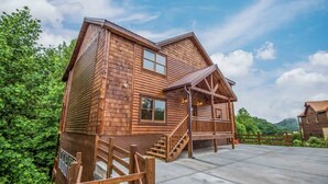 A log cabin with a porch, a staircase, and a fenced driveway. - Epic Stay: Private Pool, Theater & Games for 30 (Sevierville)