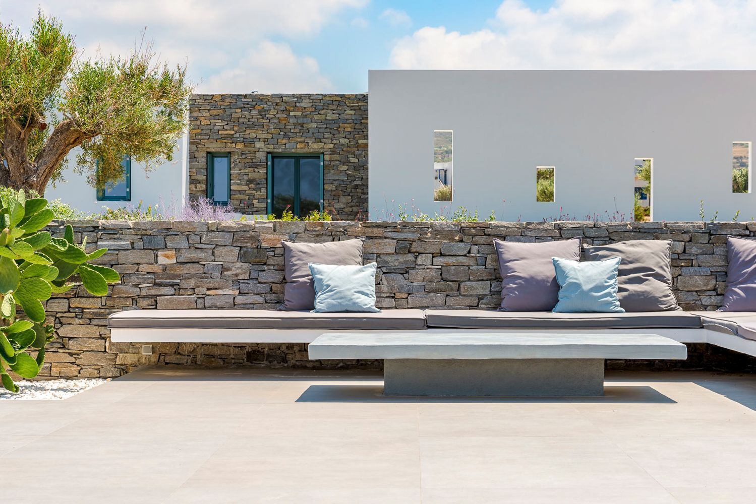 Un área de estar exterior moderna con muros de piedra y un banco.