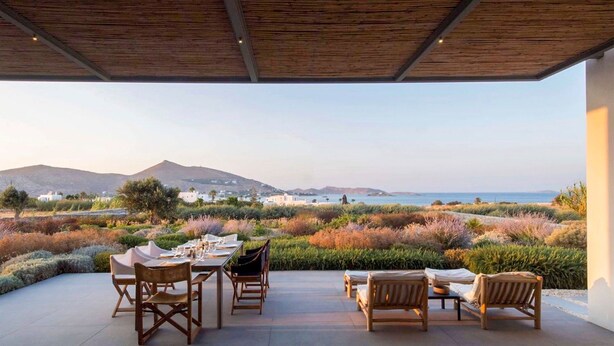 Un espace extérieur aménagé pour prendre les repas, avec vue sur la mer et les collines.