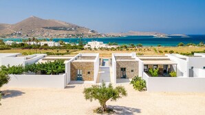 Une propriété située sur la côte, avec des bâtiments blancs, une vue sur la mer et une montagne en arrière-plan.