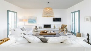 Un salon moderne avec un canapé blanc, une table basse, un luminaire suspendu et une cheminée.