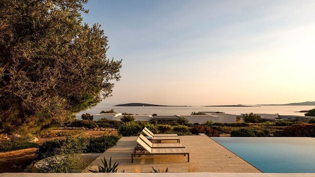 A poolside area with lounge chairs, a view of the sea, and a landscaped garden. - Villa Irina - Five Bedroom Villa, Sleeps 10 (Makria Miti)