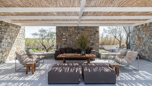 Un patio al aire libre con paredes de piedra, una mesa de madera y asientos.