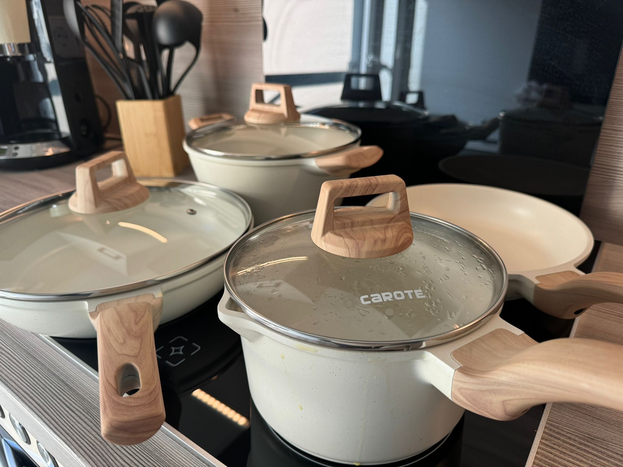 Three white pots with wooden handles on a stove.
