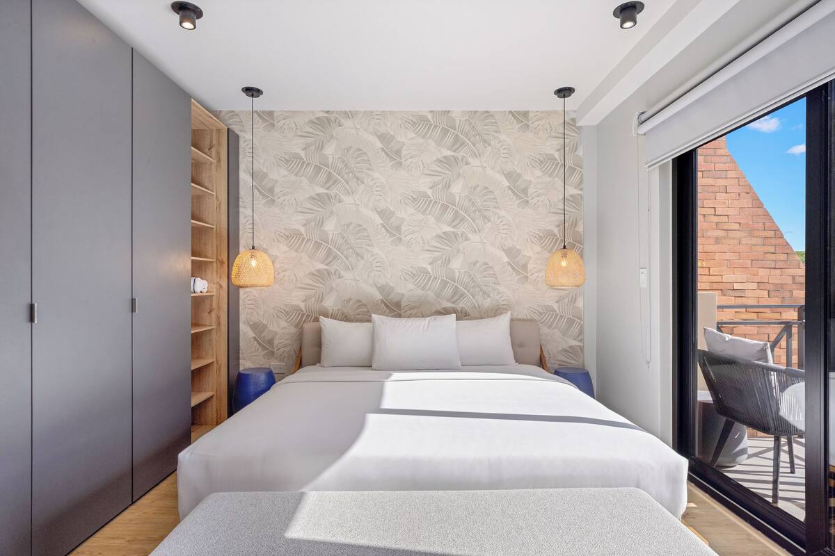 Un dormitorio moderno con una cama grande, armario empotrado y vistas al exterior.