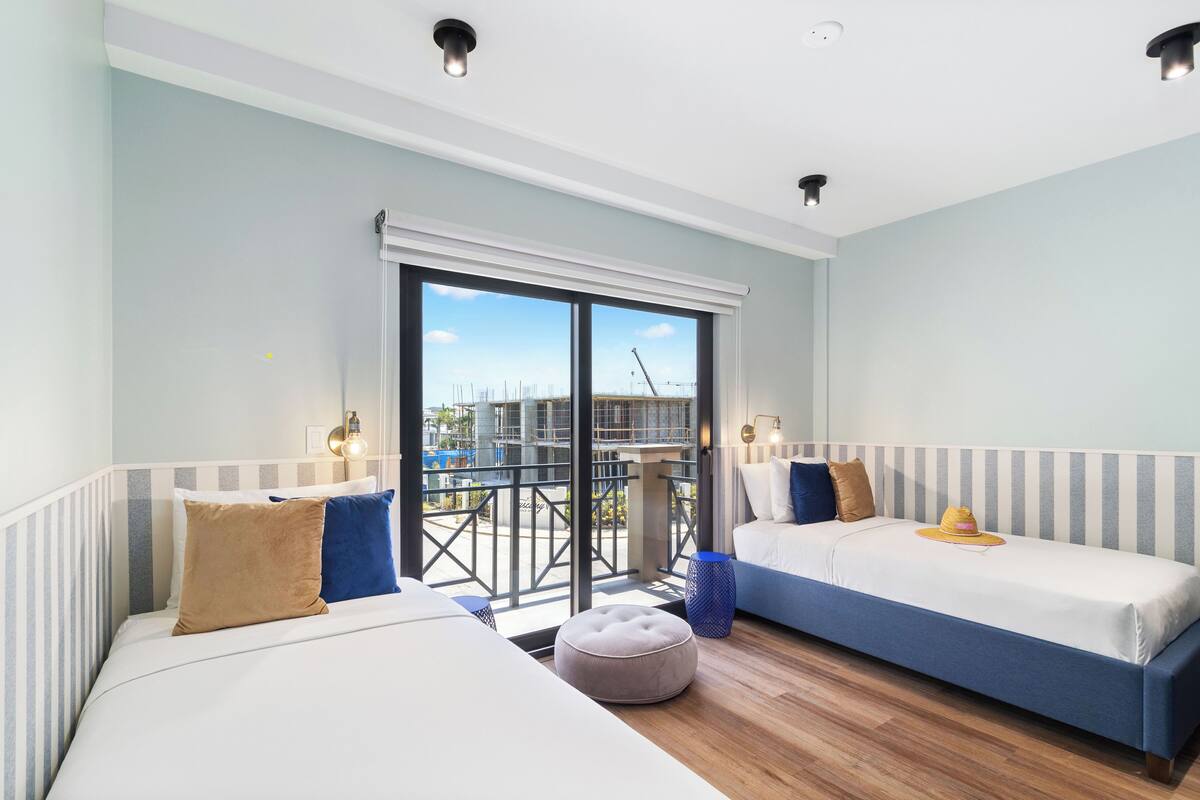 Una habitación de hotel moderna con dos camas, un balcón y vista a la ciudad.