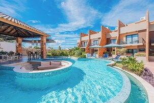 A swimming pool with a sun deck, lounge chairs, and a covered seating area.