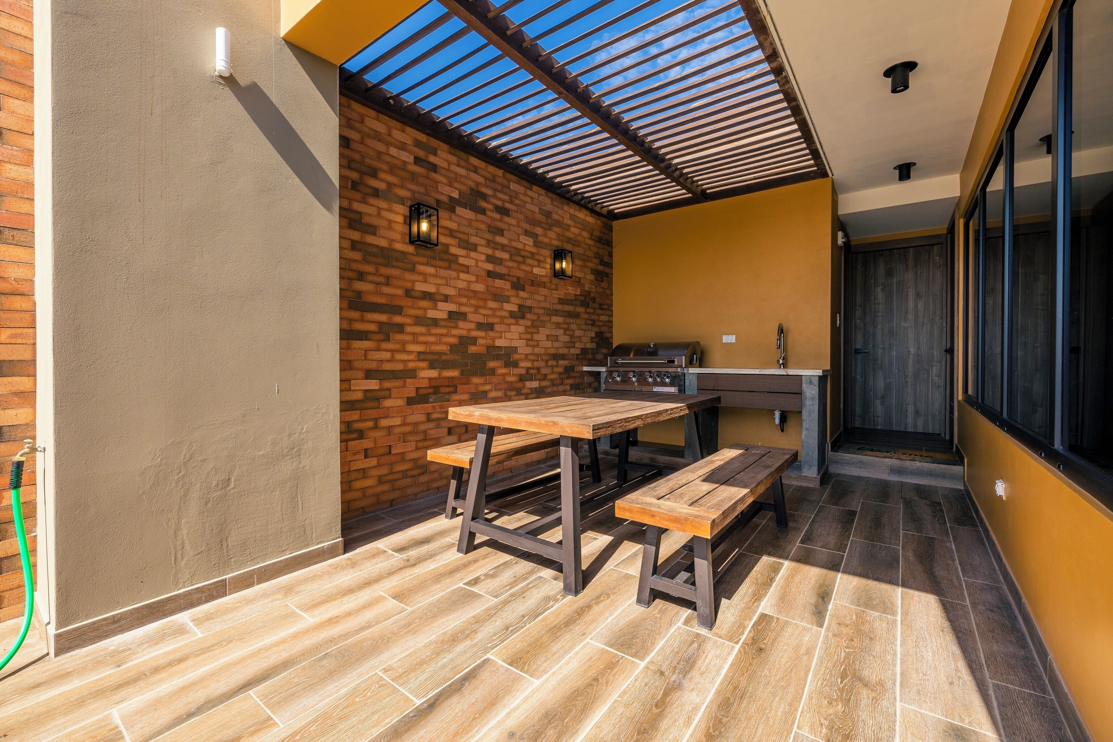 A patio with a brick wall, a wooden table, and a bench.
