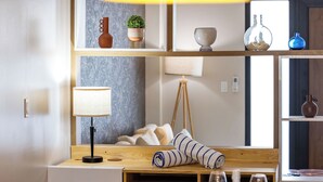 A modern room with a wooden desk, a lamp, a small plant, and a window with a view. - Bocobay Porta al Sole Condos (Noord)