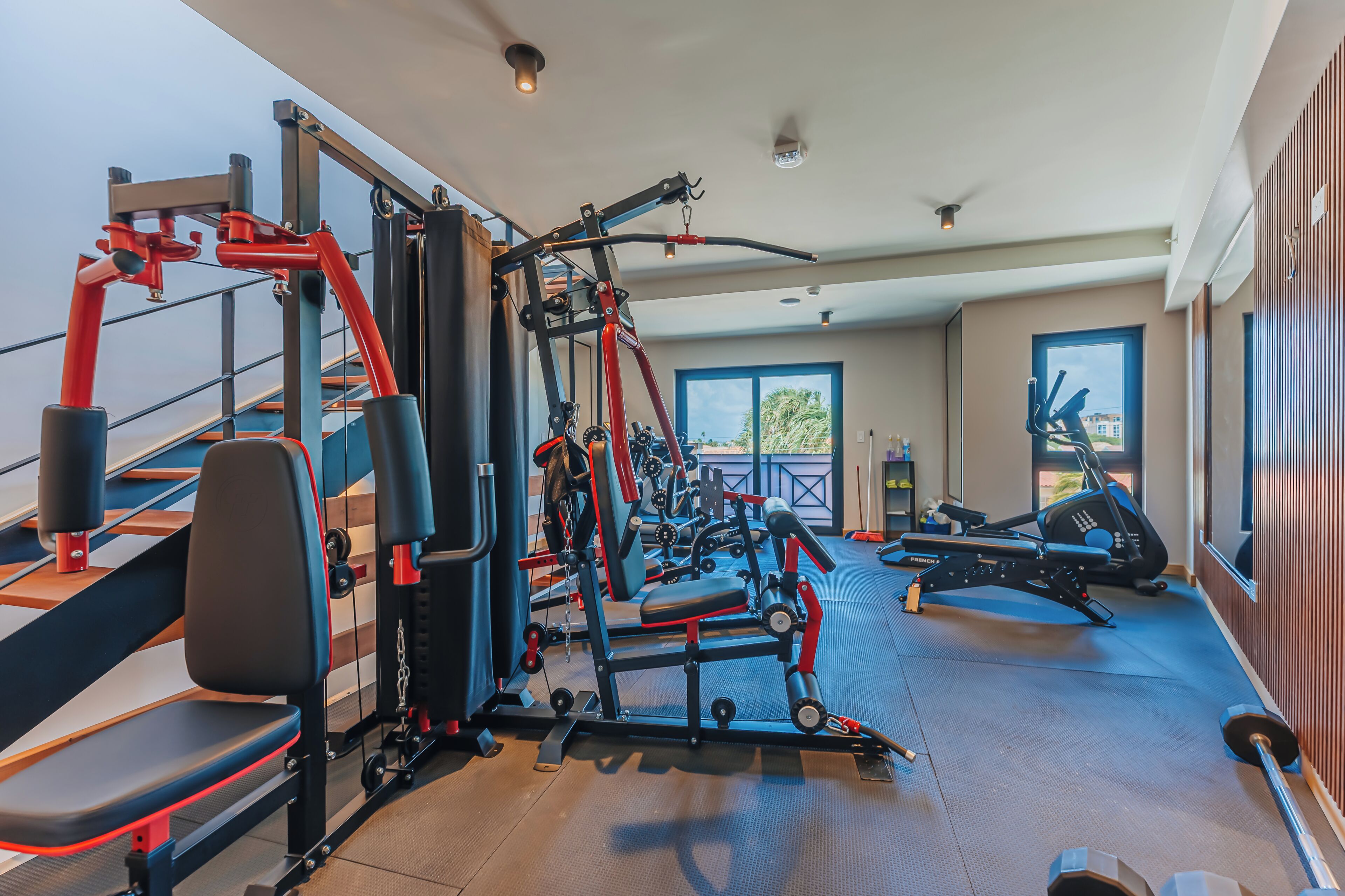 A gym with various exercise equipment, a treadmill, and a rowing machine.