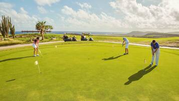Ein Golfplatz mit freiem Blick auf das Meer und ein paar Kakteen im Hintergrund.