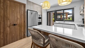 A modern kitchen with a large island, wooden cabinetry, and a view of the outdoors. - Bocobay Porta al Sole Condos (Noord)
