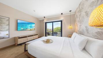 Habitación de hotel con una cama grande, un televisor montado en la pared, un balcón con vistas al mar y una lámpara de pared decorativa.