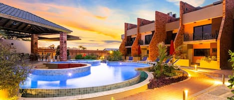 Un resort con piscina, mobiliario exterior y un patio cubierto.