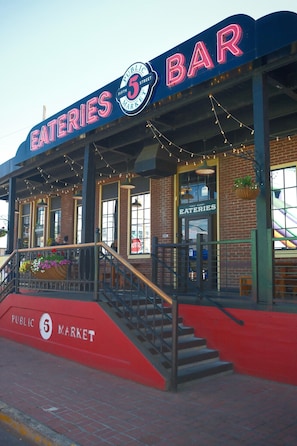 A brick building with a sign reading 'EATIES BAR' and 'PUBLIC 5 MARKET' on the facade.