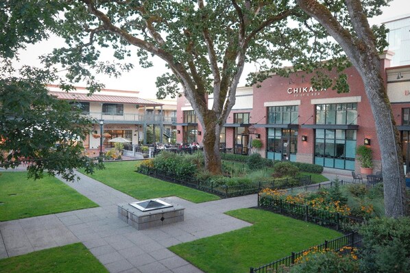A courtyard with a large tree, a fire pit, and a building with a sign reading 'CHIKA.'