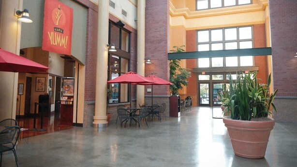 A spacious indoor area with a café sign, multiple tables with red umbrellas, and potted plants. - Lilac Home-Cozy home w/hot tub. Walking distance to Autzen, fine dining/shopping (Eugene)