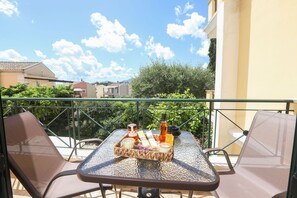 A balcony with a table set for two, featuring a tray with candles, snacks, and a bottle.