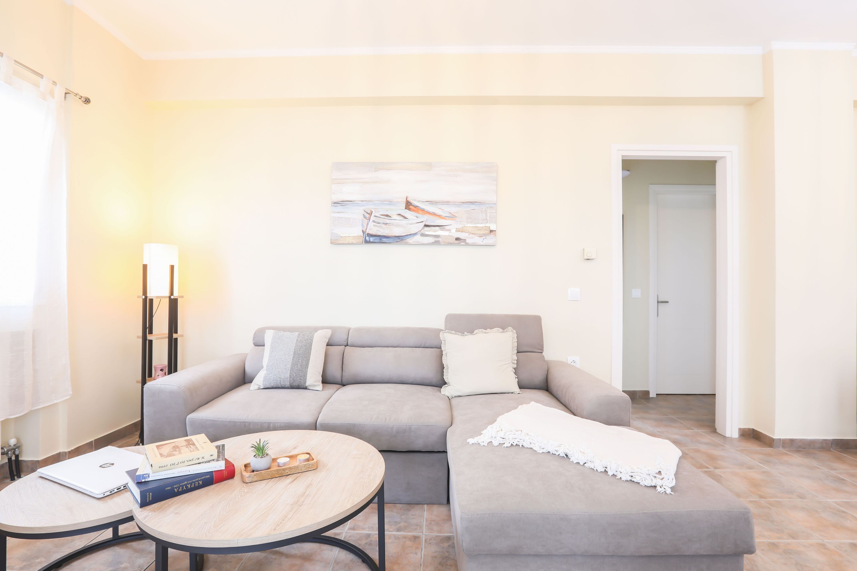 A living room with a grey sofa, a round wooden coffee table, and a painting on the wall.
