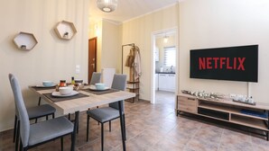 A modern living room with a dining area, a TV mounted on the wall, and a coat rack. - Smart Home Corfu Apartment (Corfu)