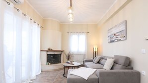 A living room with a fireplace, a sofa, a coffee table, and a painting on the wall. - Smart Home Corfu Apartment (Corfu)