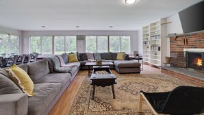 Un salon moderne avec un canapé d’angle, une table basse, une cheminée et une bibliothèque.