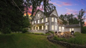 Une grande maison à deux étages, dotée d’un porche abrité, d’un foyer en pierre et d’une pelouse bien entretenue.