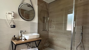 Une salle de bain moderne avec une douche à parois de verre, un miroir rond et un meuble-lavabo en bois.