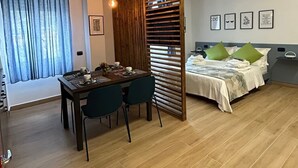 Une chambre moderne avec un coin repas, un lit agrémenté d’oreillers verts et une cloison en bois.