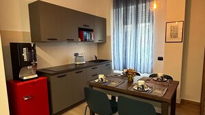 Une cuisine de taille réduite avec un appareil électroménager rouge, une table à manger avec des chaises et un luminaire suspendu.